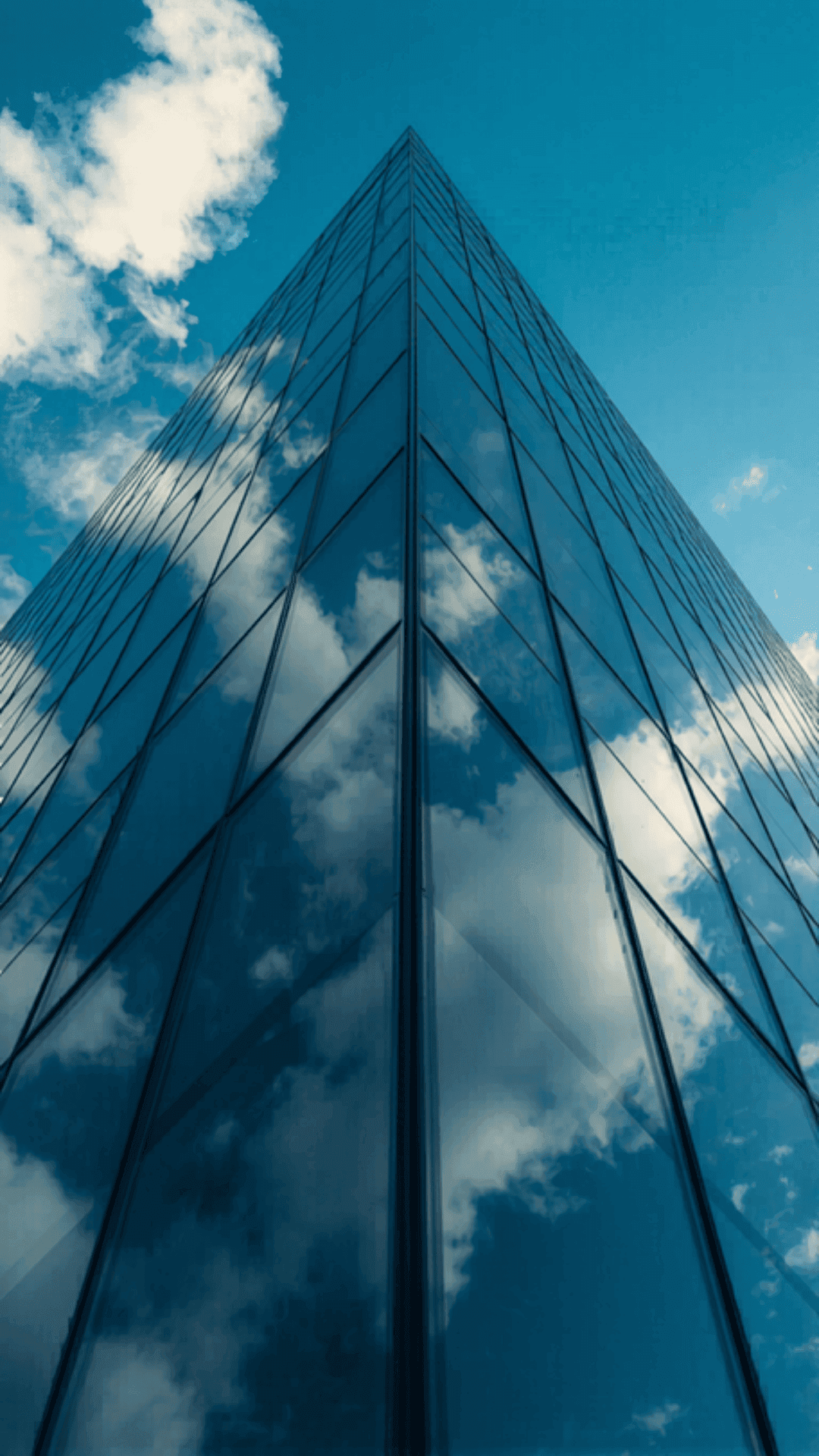 Edificio moderno de cristal con el cielo y nubes reflejados — representación de solidez institucional